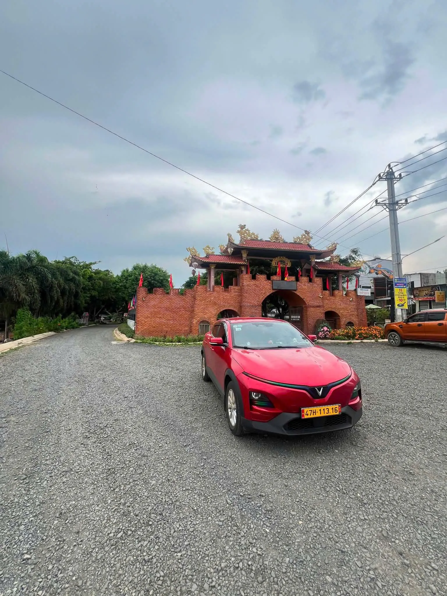 Xe taxi điện trước cổng chùa xây gạch đỏ