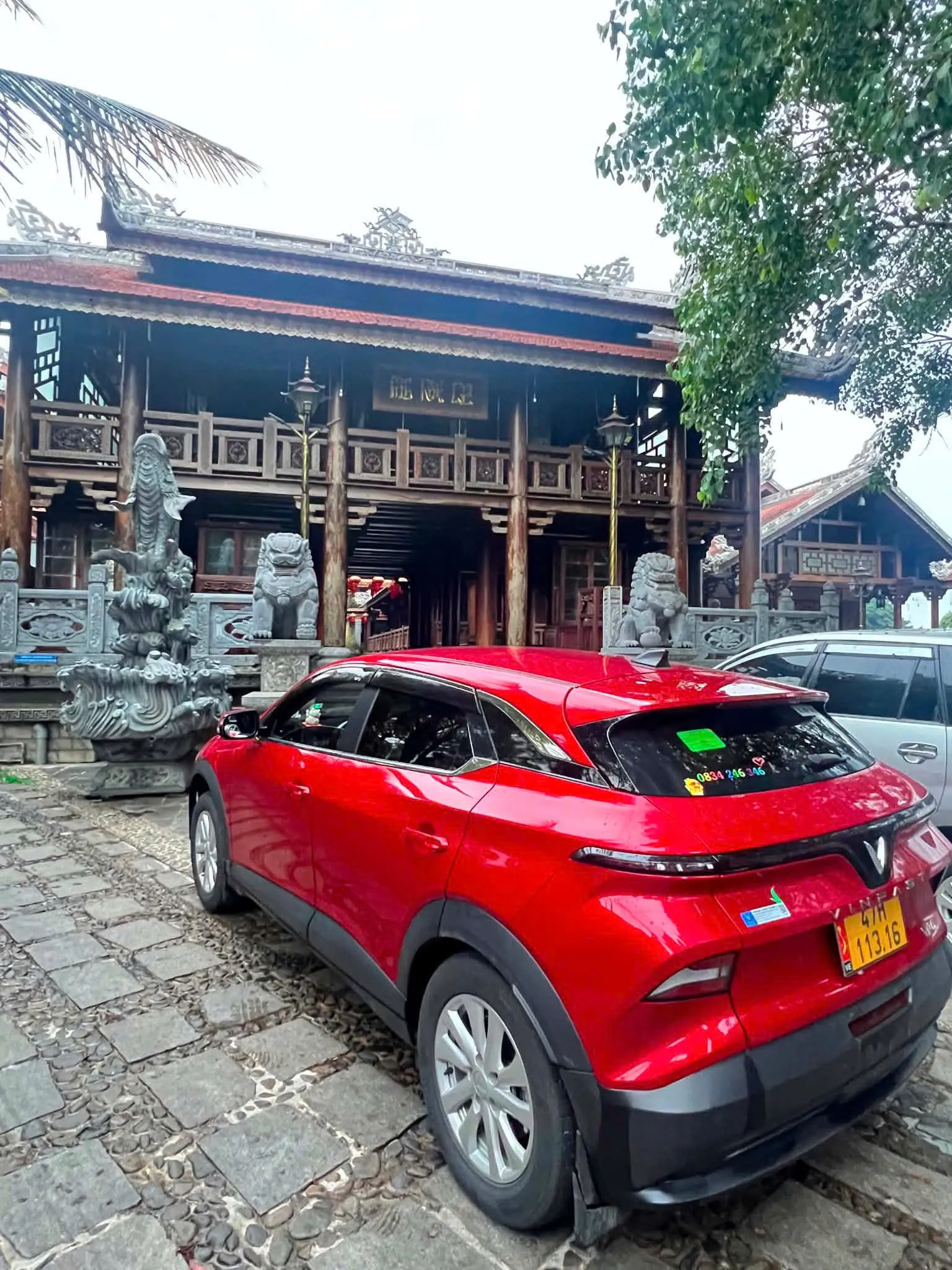 Xe taxi điện trước một ngôi đình gỗ ở xã Ea Kly